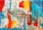 An abstract painting featuring bold, vibrant brushstrokes and splashes of color. The composition includes large areas of red, yellow, turquoise, and orange, interspersed with grey and white, creating a dynamic sense of movement. The use of black lines adds contrast and depth to the piece.