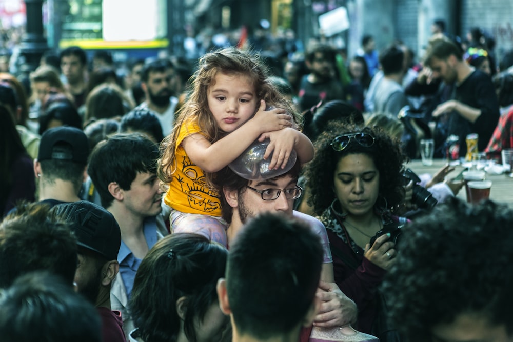 girl sitting on man's shoulder