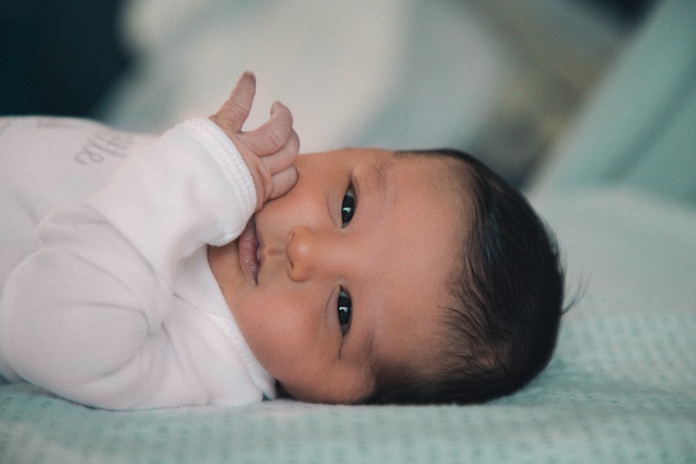 baby in white shirt lying on bed