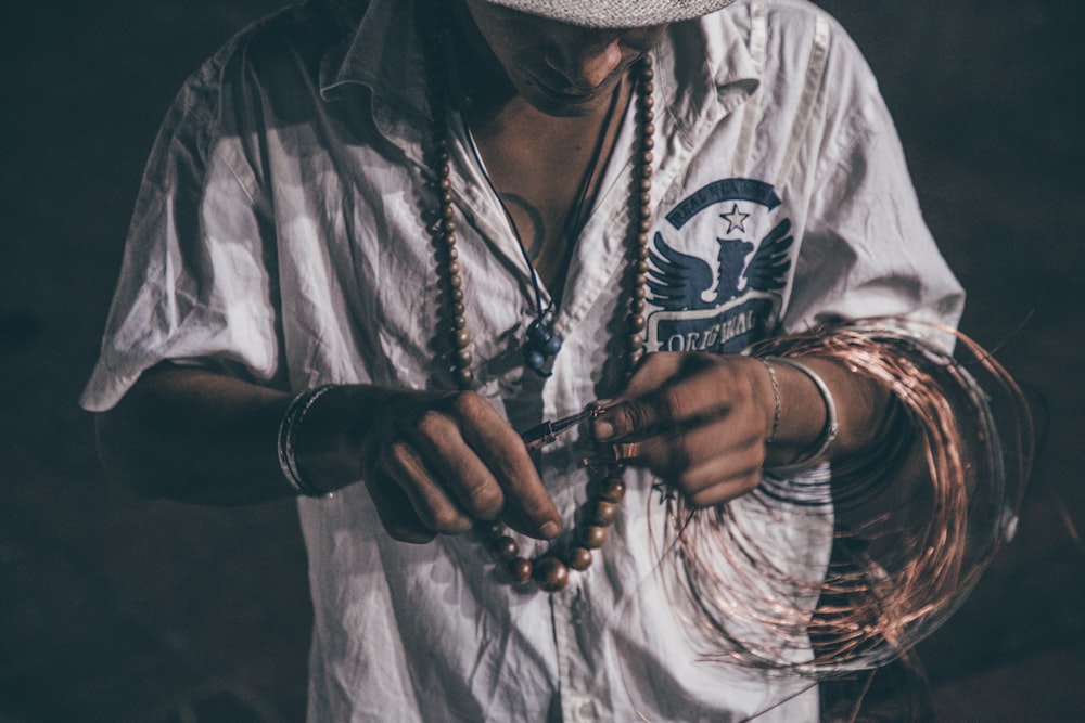 man in white button up shirt holding copper wire