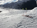 A pair of sleek skis resting against a snowy mountain backdrop under clear blue skies.