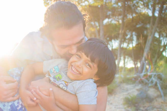 man kissing child during golden hour