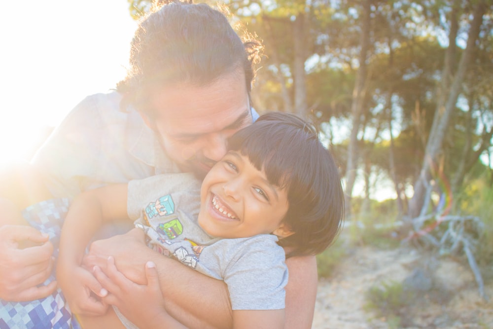 man kissing child during golden hour