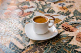A steaming cup of coffee on a vintage ceramic saucer with a backdrop of traditional Mexican textiles.