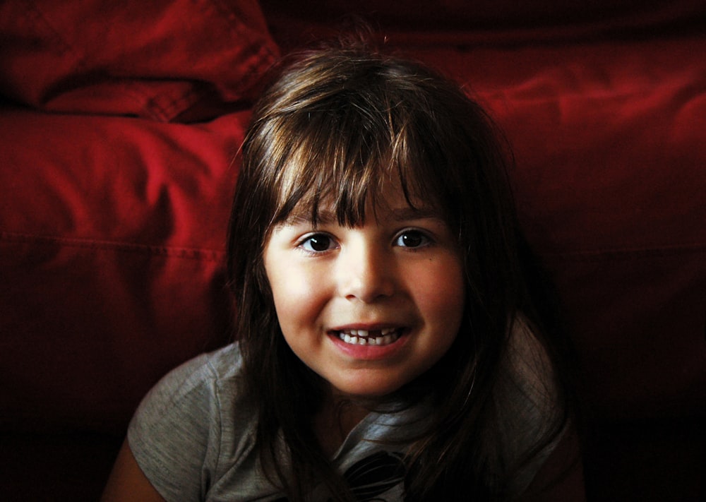 girl wearing gray crew-neck shirt near red textile