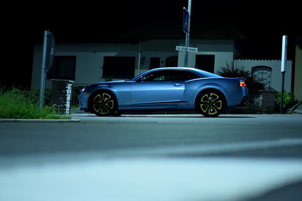 blue coupe parked beside building during daytime