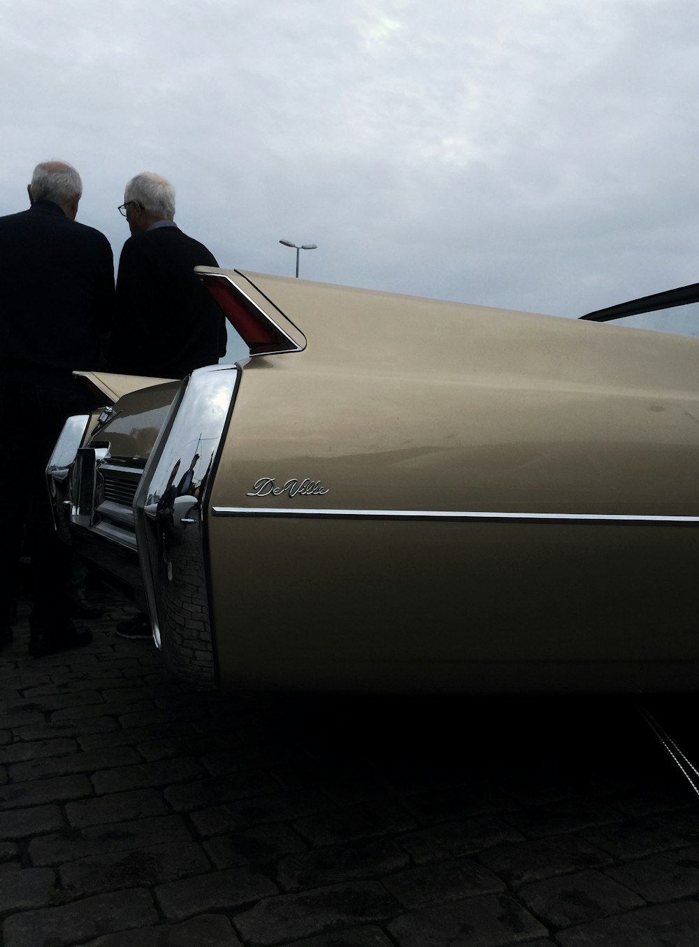 two men beside gold car