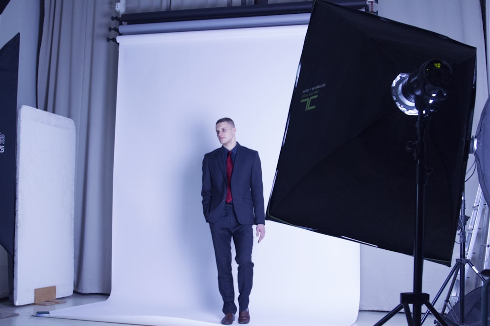 man in black suit standing beside canvas inside studio