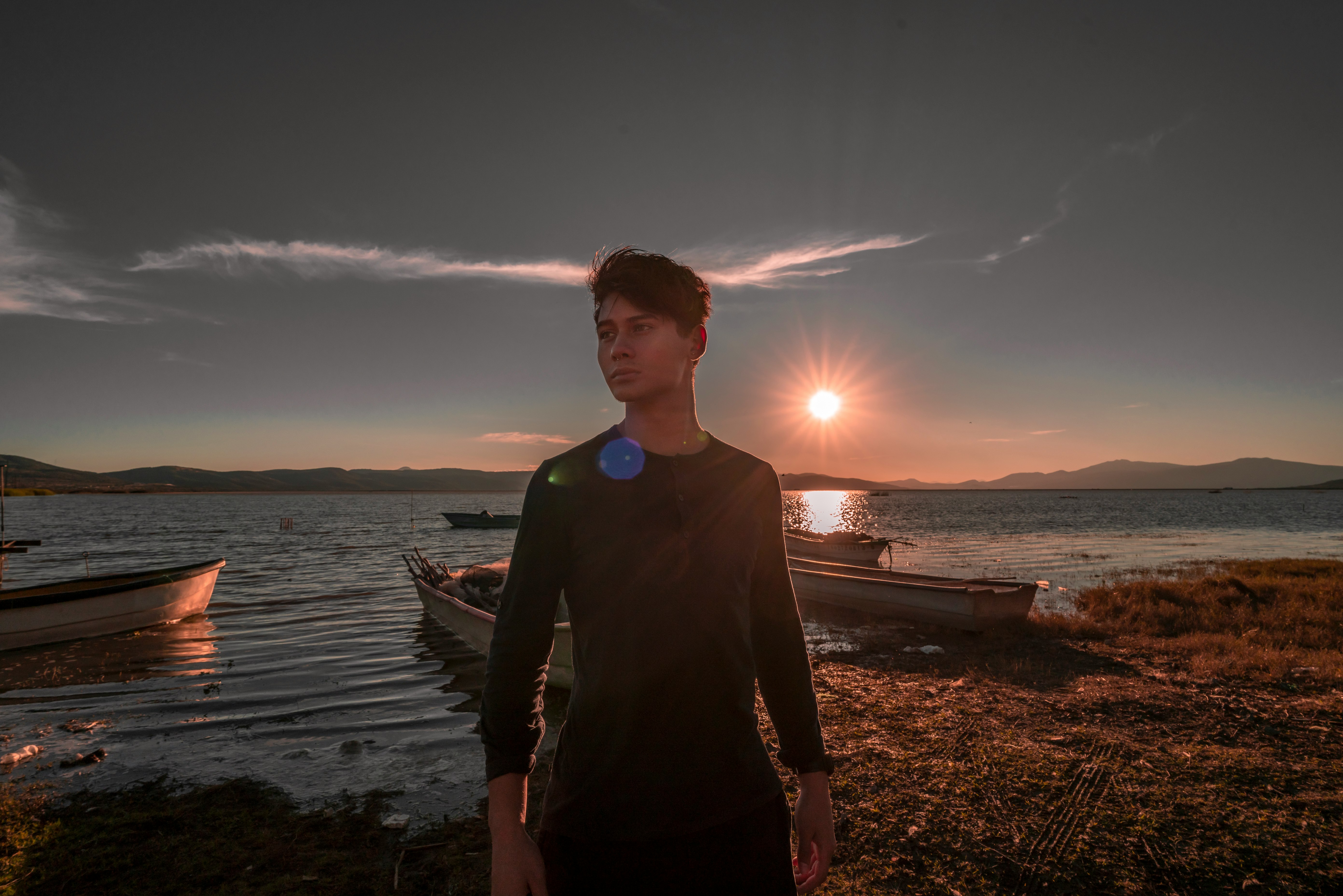 man wearing black crew-neck sweater standing near the body of water