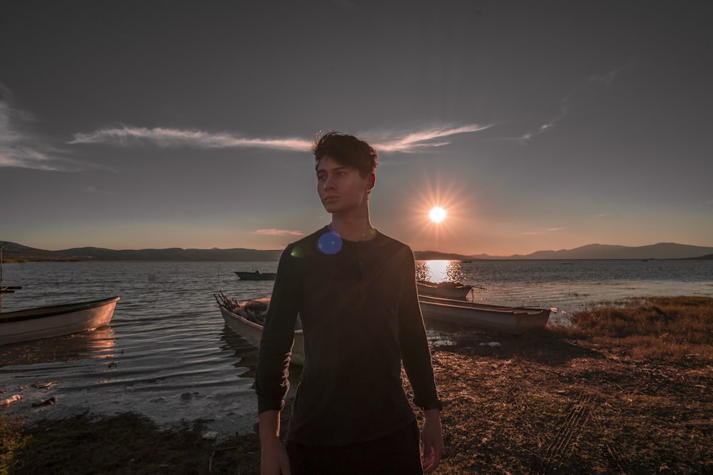 man wearing black crew-neck sweater standing near the body of water