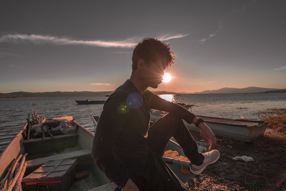 man sitting on white boat near ocean