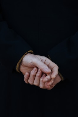 Hands clasped in a moment of focus during a workshop, showing the texture of worn denim and paper.