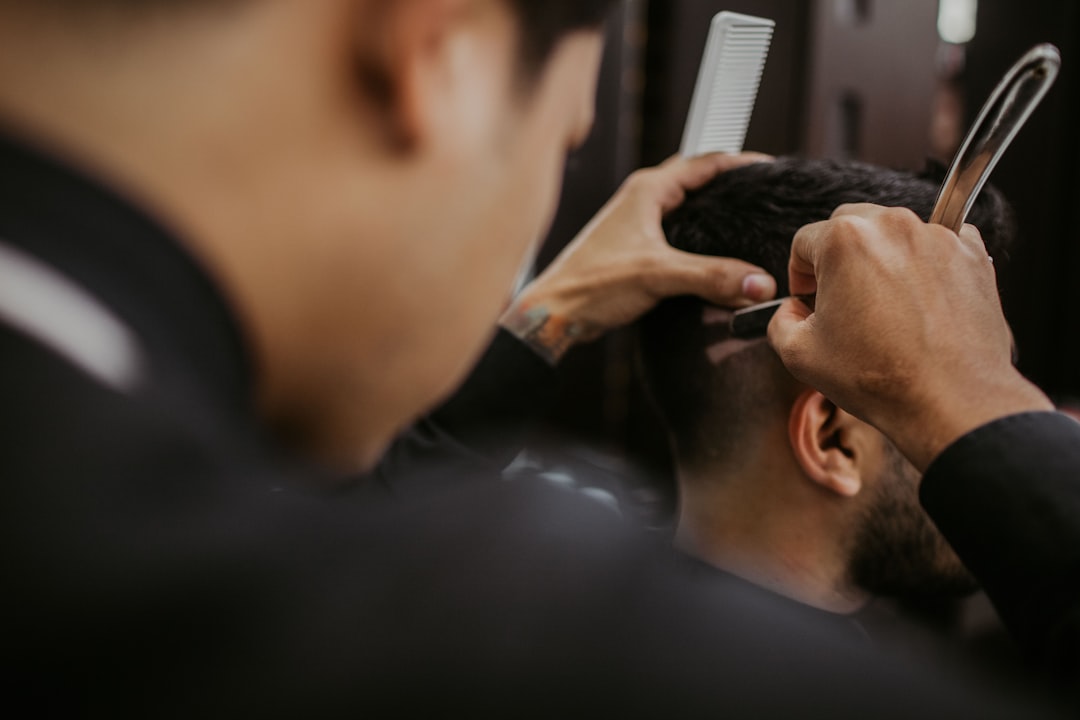 selective focus photography of person cutting hair of man