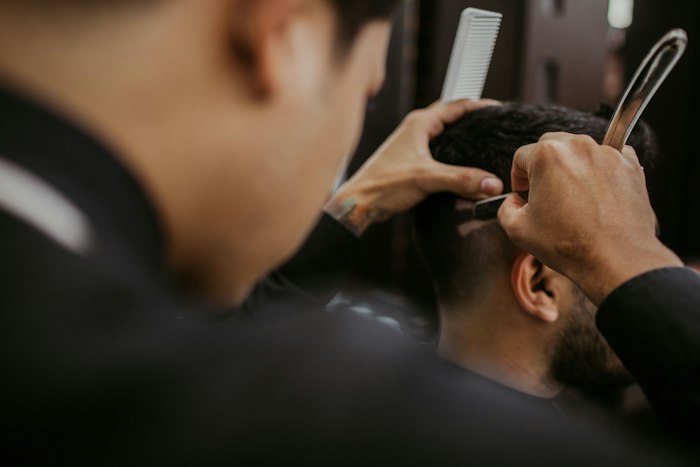 Barber working a straight razor and comb along a client's hairline