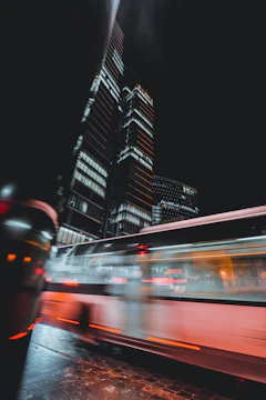 Futuristic electric buses and bikes moving through a sleek cityscape illuminated by teal and cyan lights.