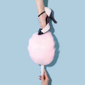 woman in blakc and white T-strap heeled sandal stepping on pink cotton candy