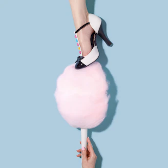 woman in blakc and white T-strap heeled sandal stepping on pink cotton candy