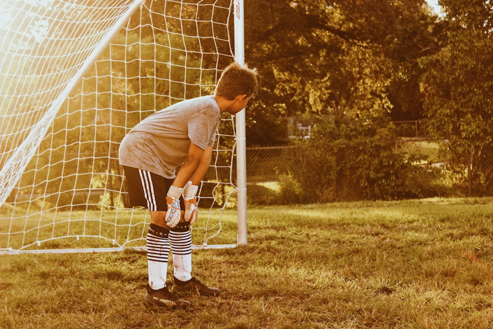 boy standing on soccer goal net