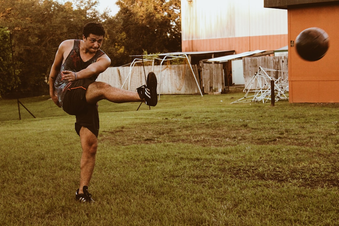 man kicking brown soccer ball