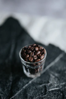 A deep shadowed image of fine glassware catching faint golden reflections beside roasted beans