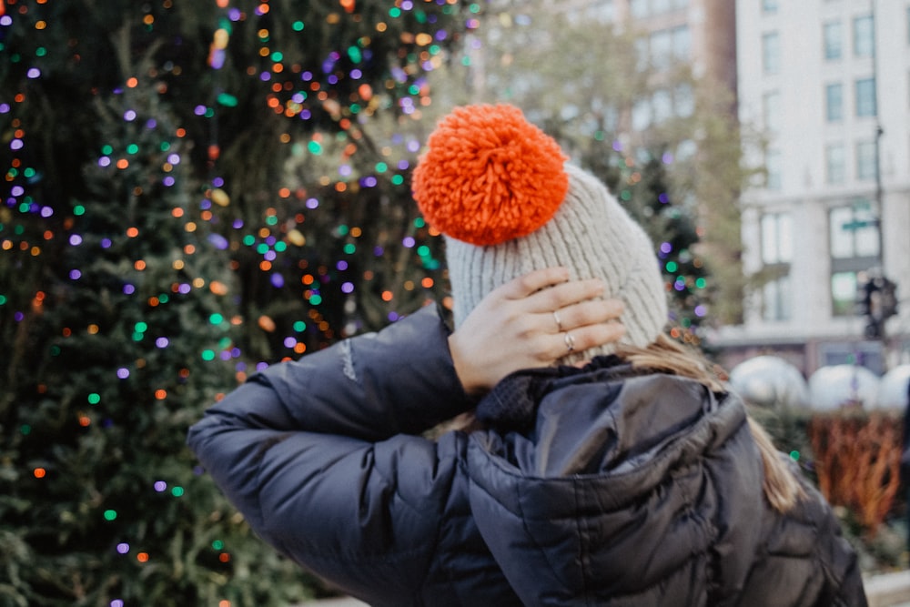 woman wearing black hoodie with knit cap near christmas tree