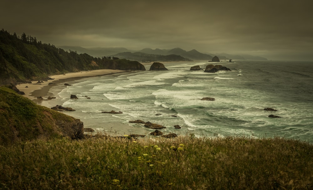 sea beside mountains under cloudy sky