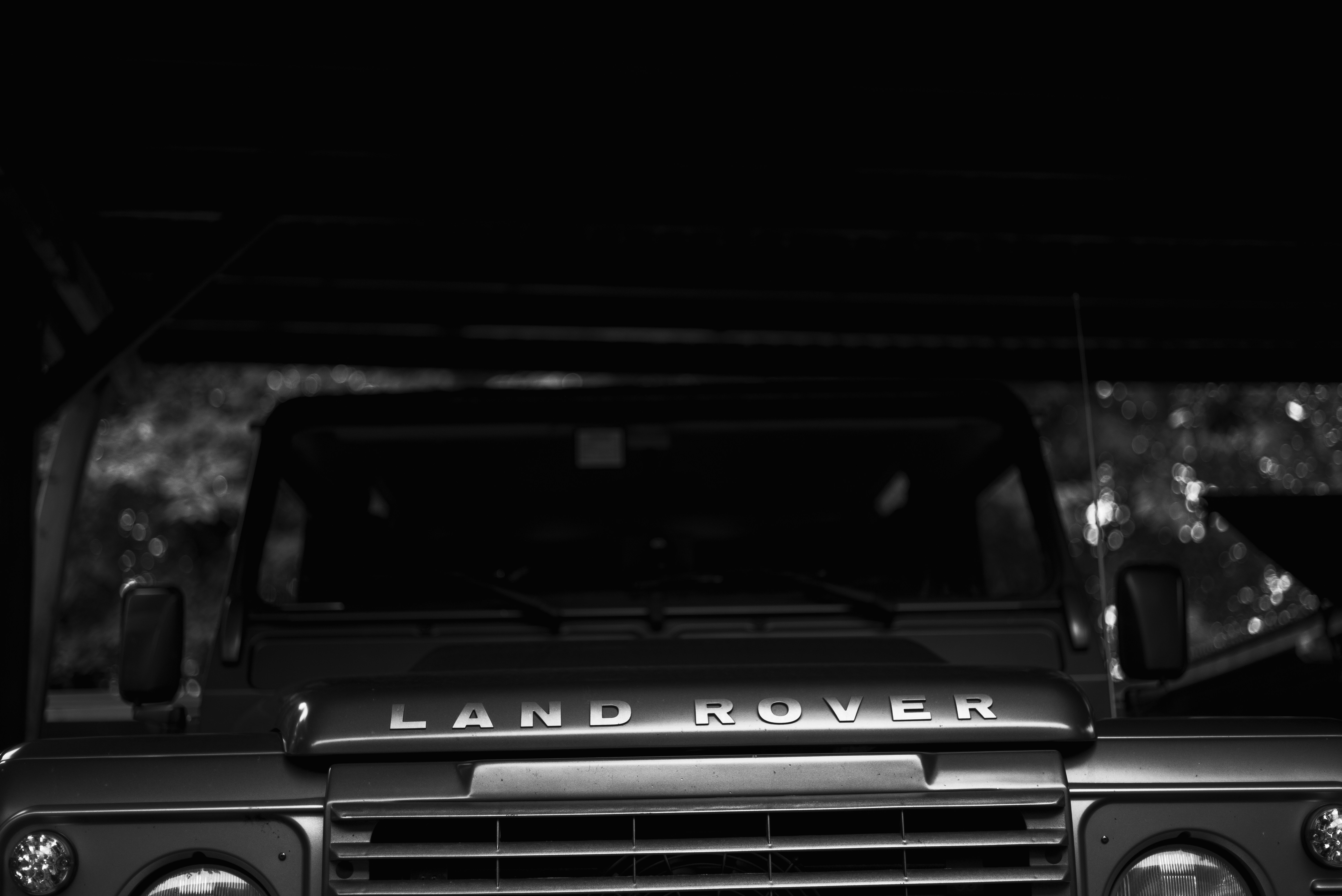 Front-angle view of a Land Rover's grille and emblem in moody, low-light tones.