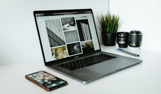 A sleek laptop surrounded by various computer accessories like keyboards, mice, and RAM sticks on a clean white desk.