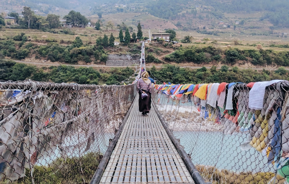 person walking on bridge with clothes hanging