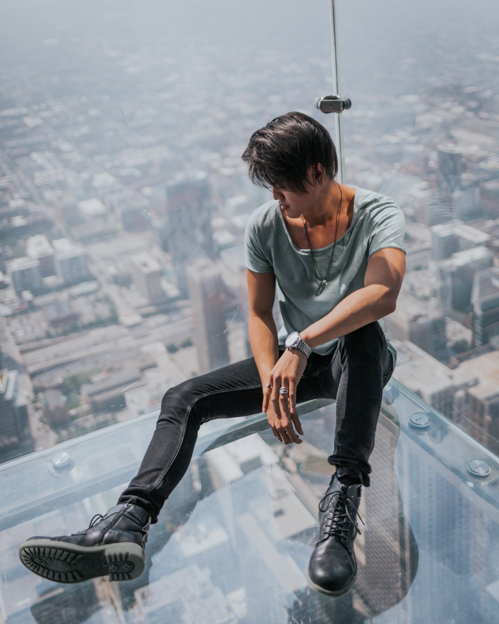 man sitting on top of clear glass roof top