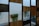 Several vertical panels alternate between dark and medium wood tones, creating a geometric pattern. Behind the panels, green leafy vines hang down from rectangular planters attached to a white wall, adding a natural element to the structured design.