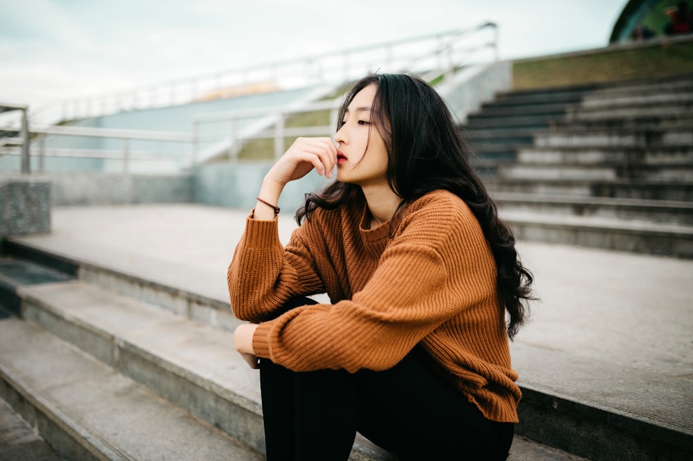 입술을 들고 갈색 스웨터를 입고 있는 여자