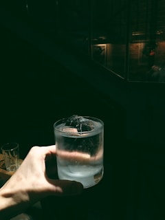 Bartender carefully placing a clear ice cube into a glass, highlighting precision and care.