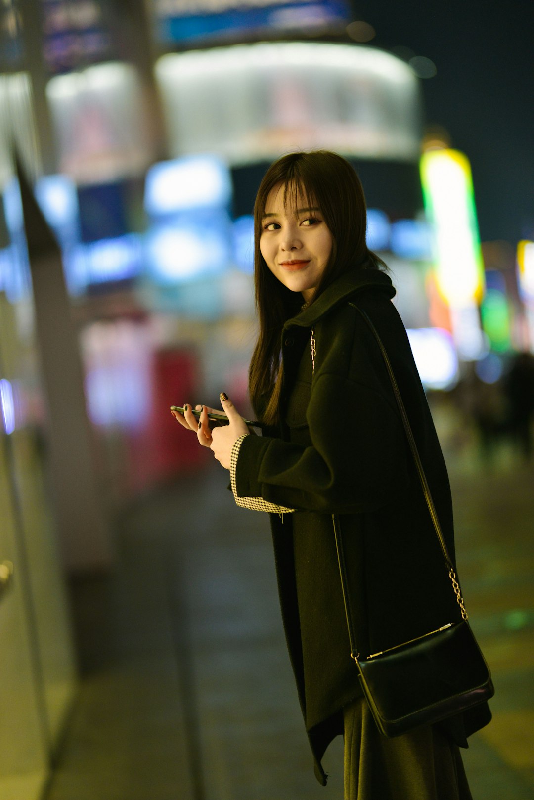 woman in black coat on grey tiled pathway during nighttime