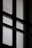 A close-up view of a window with a mesh screen, creating a grid-like pattern that contrasts with the light coming through the glass panes.
