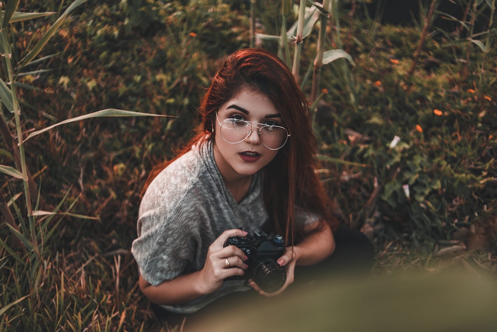 Frau hält Kamera, während sie auf Gras sitzt