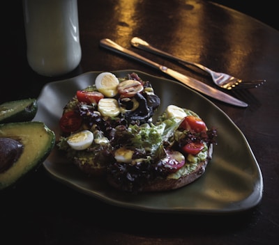 A close-up shot of a beautifully styled avocado toast with fresh herbs and edible flowers on a rustic wooden table.