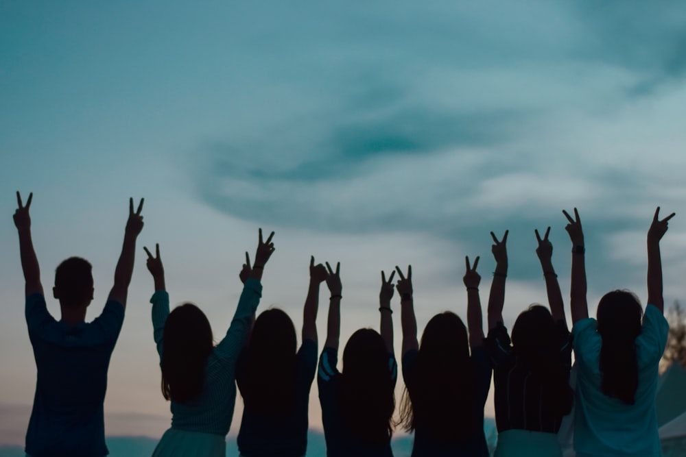 seven person raising hands across clouds