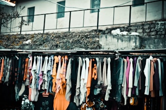 Colorful fashion accessories including scarves, hats, and sunglasses displayed on a rustic wooden rack.