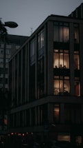 A sleek modern London apartment building glowing warmly at dusk.