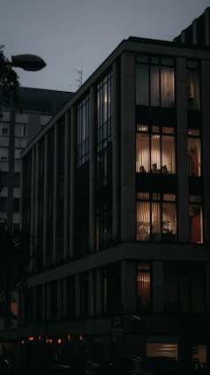 A modern, inviting residential building with warm lighting at dusk, reflecting a welcoming community vibe.