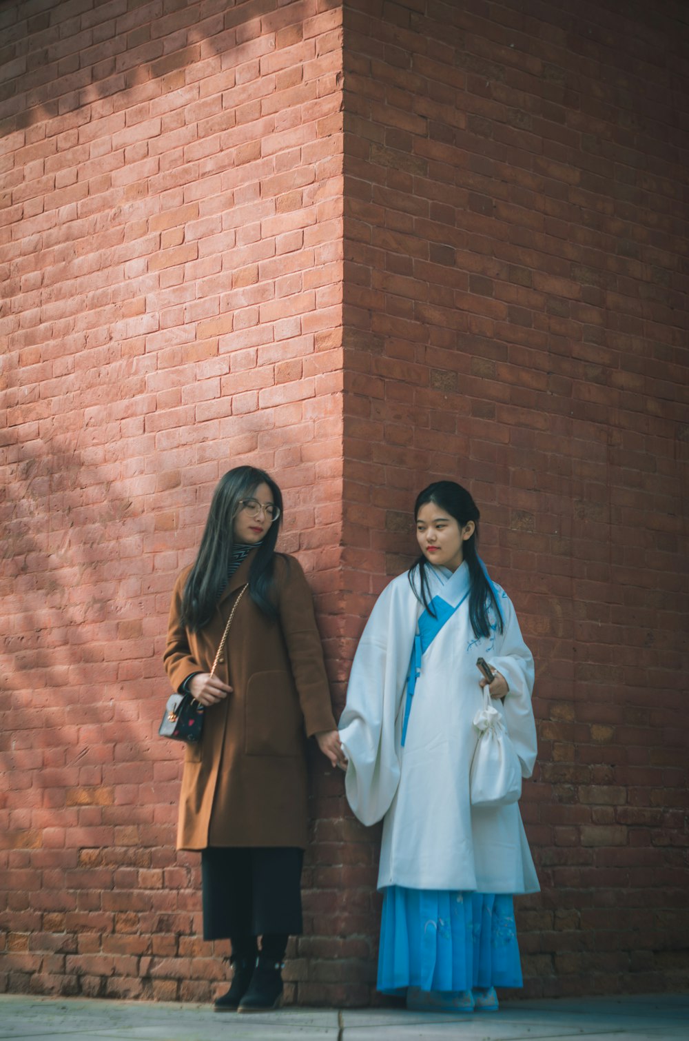 two women holding hands near wall