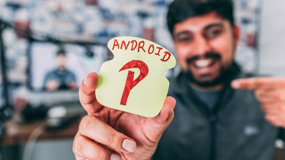 man holding white cut-out paper with android P print