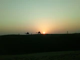 A warm sunset over the Sahara desert with a caravan of camels in silhouette.