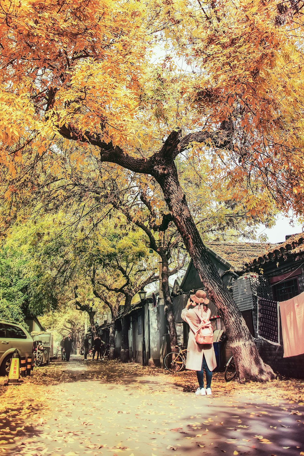 Frau mit Smartphone unter gelbem Baum