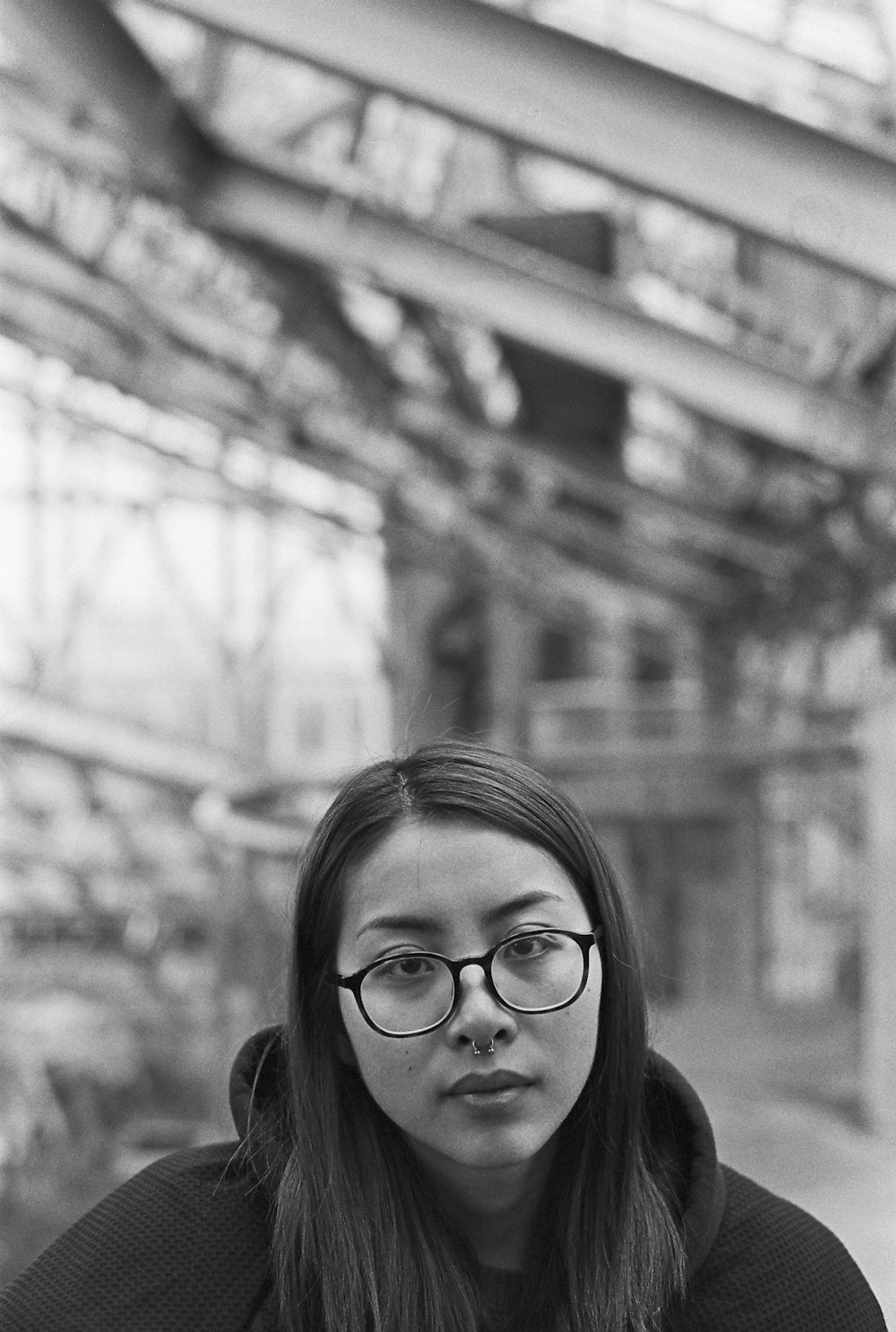 greyscale photo of woman wearing hoodie and eyeglasses