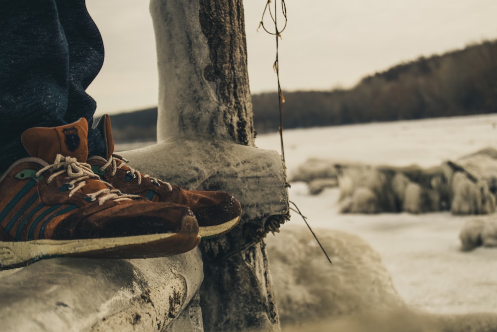 person wearing brown sneakers standing on wooden beam