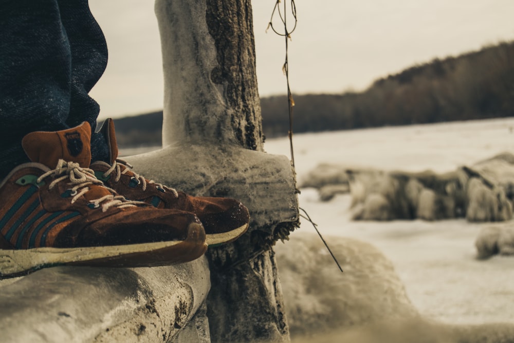 Persona con zapatillas marrones de pie sobre una viga de madera