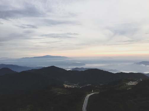 A serene landscape with a winding road leading to distant mountains.