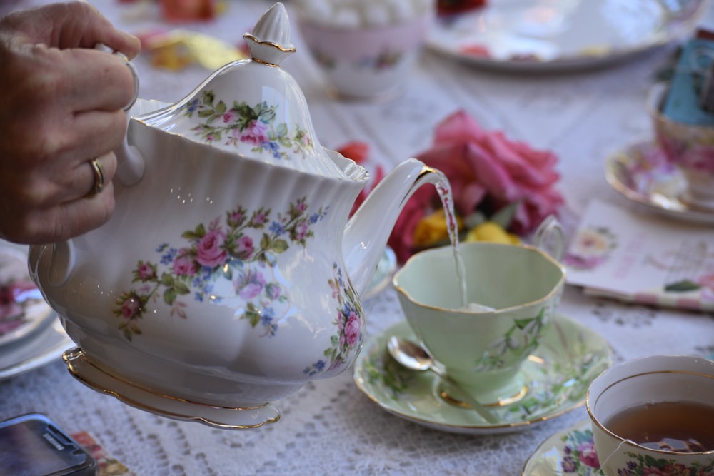 person holding white ceramic teapot